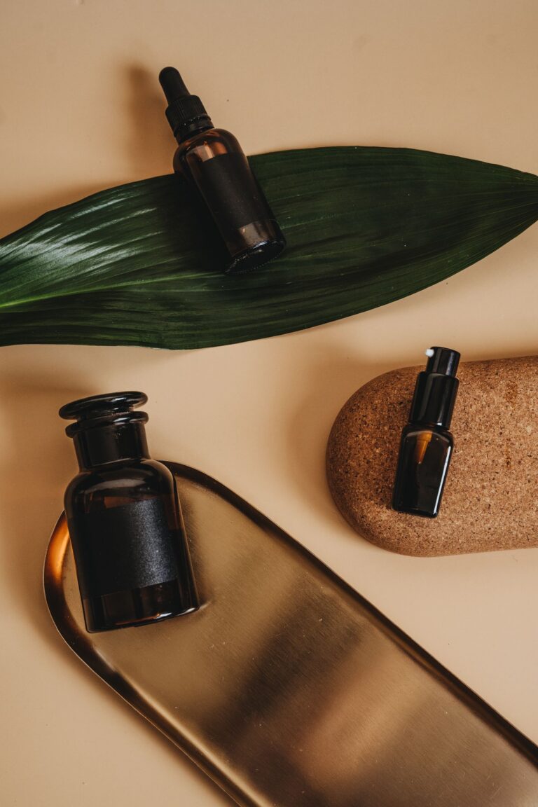 Frascos de cosmético sobre uma folha verde e uma bandeja dourada